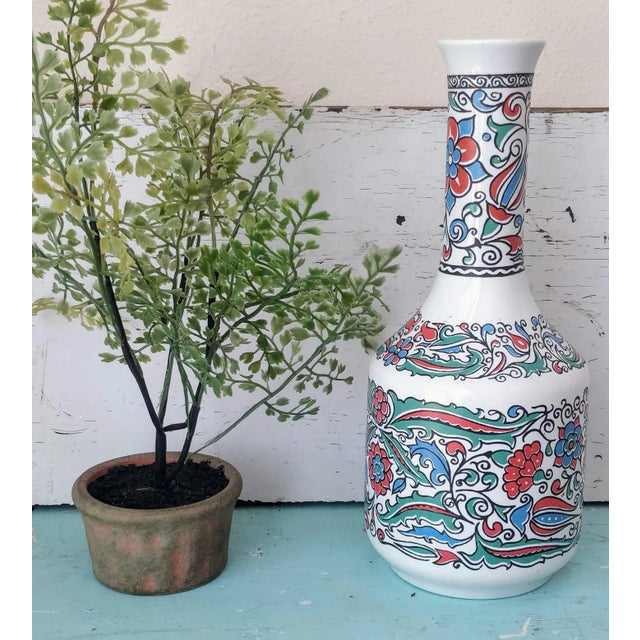 This bright and cheerful Greek vase or decanter features a fun floral design. It stands at 10.5 inches tall, with a mouth...