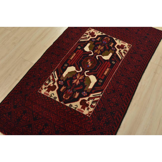 An authentic vintage tribal Baloch rug hand-knotted with fine wool and natural dyes. This nomadic oriental rug features a...