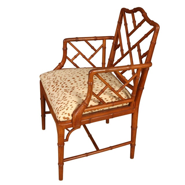 A single vintage armchair features a Chinese Chippendale bamboo style frame with a warm, medium-brown finish. The back...