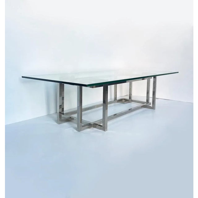Elegant vintage coffee table with an all-glass top and a polished steel frame featuring distinctive geometric interlacing...