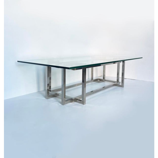 Elegant vintage coffee table with entirely glass top and polished steel structure characterized by particular geometric...