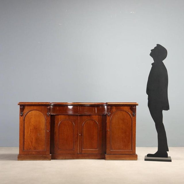 English mahogany sideboard dating from the mid-19th century, featuring an elegant and functional design. The front...