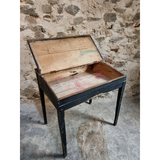This antique French school desk dates from around 1900. It features a worn matte black painted finish and a sloping...