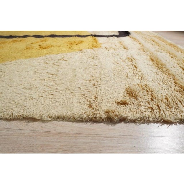 This hand knotted wool rug features a primary color palette of yellow, gold, and orange tones. Crafted in India, the rug...