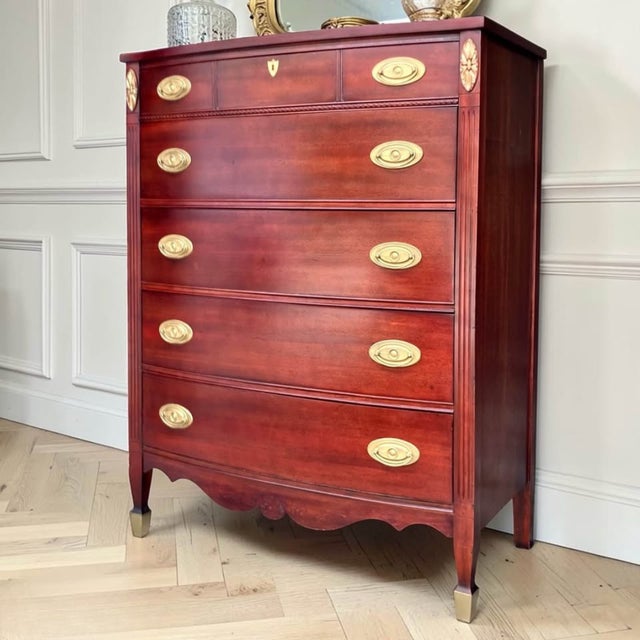 This vintage Federal-style mahogany tall chest features elegant neoclassical details including reeded corner columns,...