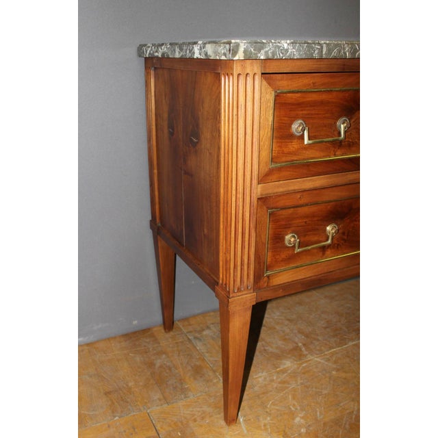 A walnut commode with brass trim, featuring two drawers, a Grey Sainte Anne marble top, a key, and a waxed finish; the...