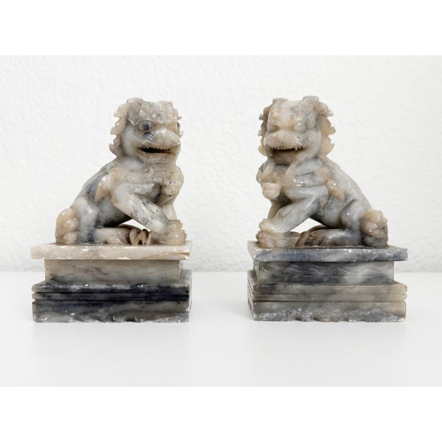 Vintage mid-20th-century pair of traditional carved soapstone Chinese foo dogs featuring a wonderful aged patina. Foo...