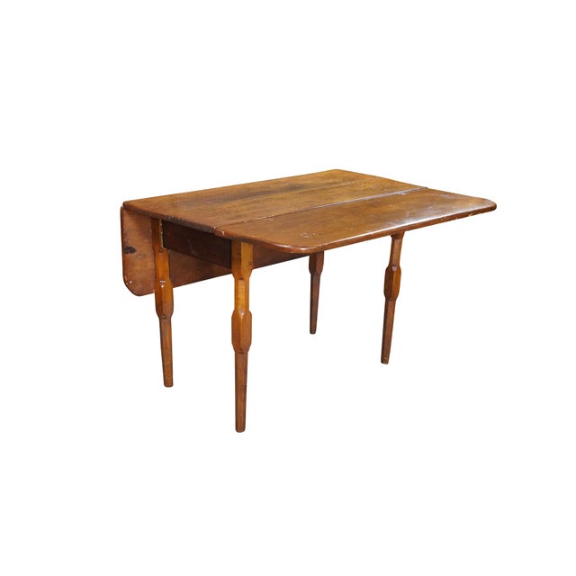 This early 19th Century American Country drop-leaf table is crafted from solid walnut and showcases the robust, functional...