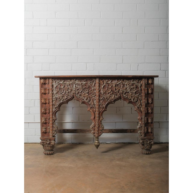An extraordinary wooden console table defined by its richly carved façade and sculptural presence. The front is composed...