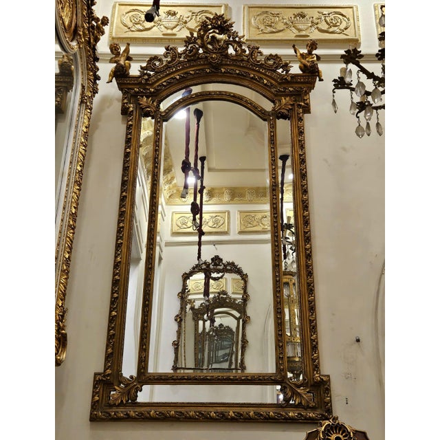 A truly magnificent French Rococo style wall mirror featuring an exceptionally elaborate gilded frame adorned with...