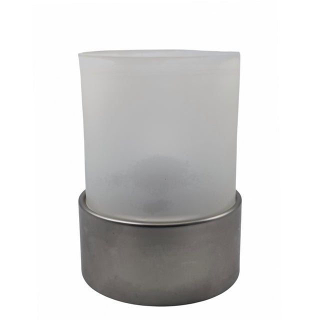 Cylindrical table lamp with diffused light. The upper section is a cylinder made of frosted opal glass. The base is...