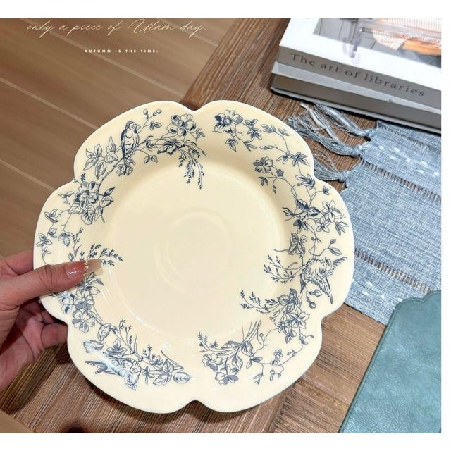 Employing underglaze painting techniques, the plate features a petal-shaped rim and is decorated with delicate blue and...