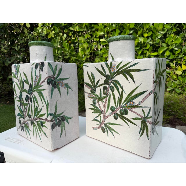 A striking pair of antique hand-painted pottery vessels featuring olive branch decoration on a richly crazed ivory...