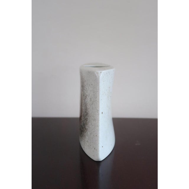 A bud vase in porcelain by virebent, made in france in the 1970s. The flattened pebble body rises to a small round...