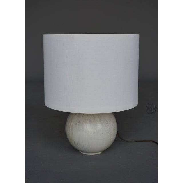 A nice lampbase by Belgium ceramicist Roger Guerin in a bulbous shape with a suble drip glaze in shades of grey and light...
