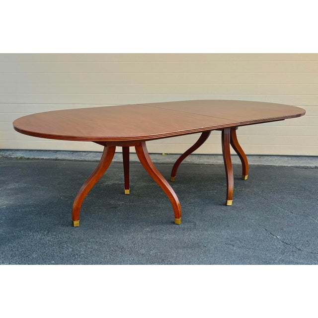 Ralph Lauren Dining Traditional Oval Table in mahogany on double pedestal with brass capped legs and optional 22”...