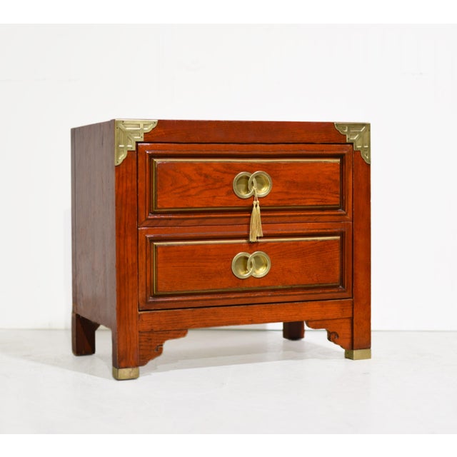 1970s Campaign Chinoiserie nightstand by Huntley for Thomasville has a rectangular wood case with a warm reddish-brown...