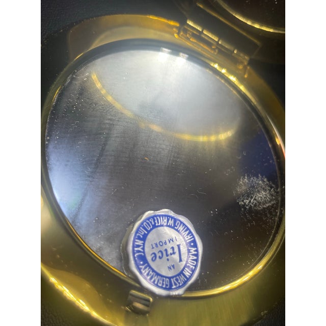 With original tags, vintage post WWII west Germany pocket compact mirror gold tone with lace front. Still secures and...