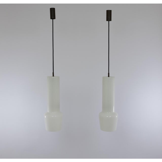 A pair of hand-blown white no. 011.11 glass pendants designed by Massimo Vignelli at the start of his impressive career in...