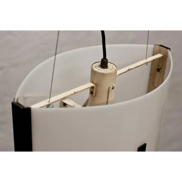 This oval ceiling lamp with suspension was produced by Stilnovo circa 1958, in acrylic glass with black painted brass...