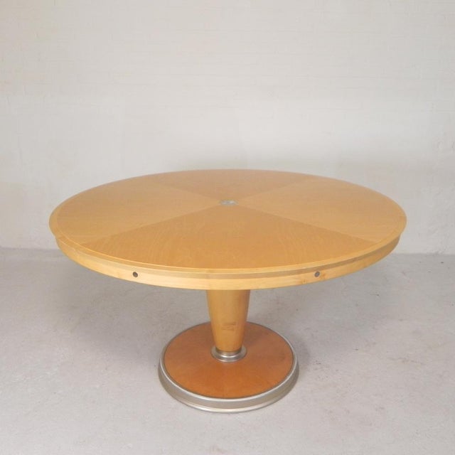 Round table made of solid veneered maple with details in matte lacquered metal. The base of the column features a matte...