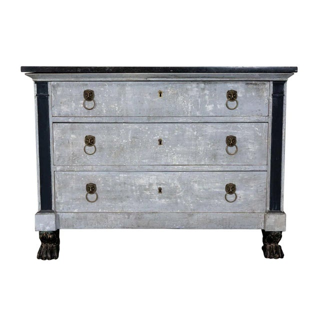 Empire commode with stone top. Three drawers with original lock and key hardware and lion head drawer pulls. Paw feet.