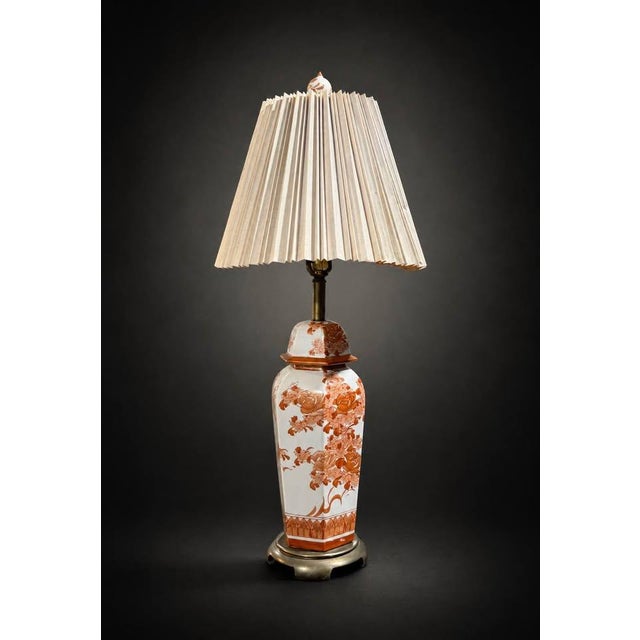 Elegant vintage porcelain table lamp featuring a detailed floral and botanical design in warm terracotta tones over a...