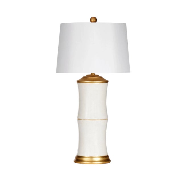 This modern table lamp with a bamboo-shaped body implements a classic color motif in cream and antique gold. The white...