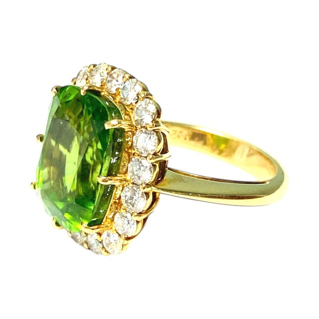 Cocktail ring crafted in 18k yellow gold, featuring a central cushion-cut peridot. The peridot is surrounded by a halo of...
