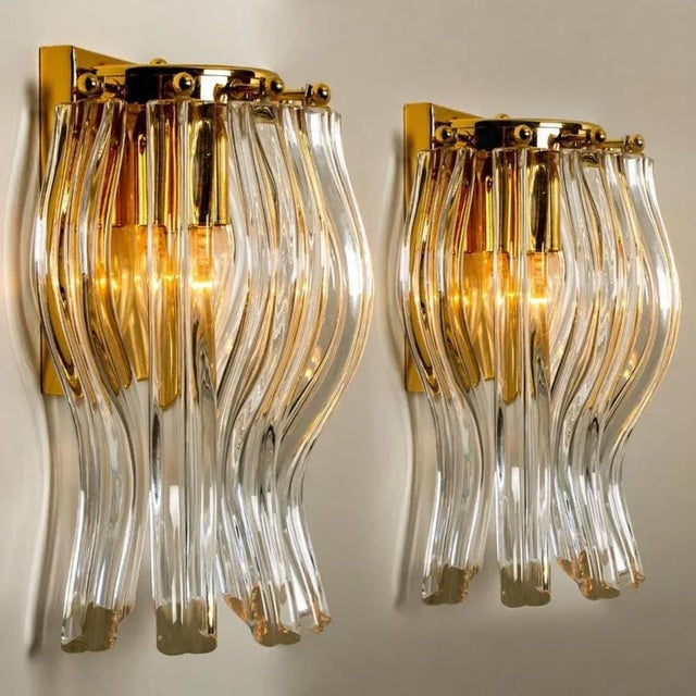 Beautiful pair of Murano glass wall sconces featuring four crystal clear glass "triete" prism-rods, with brass details and...