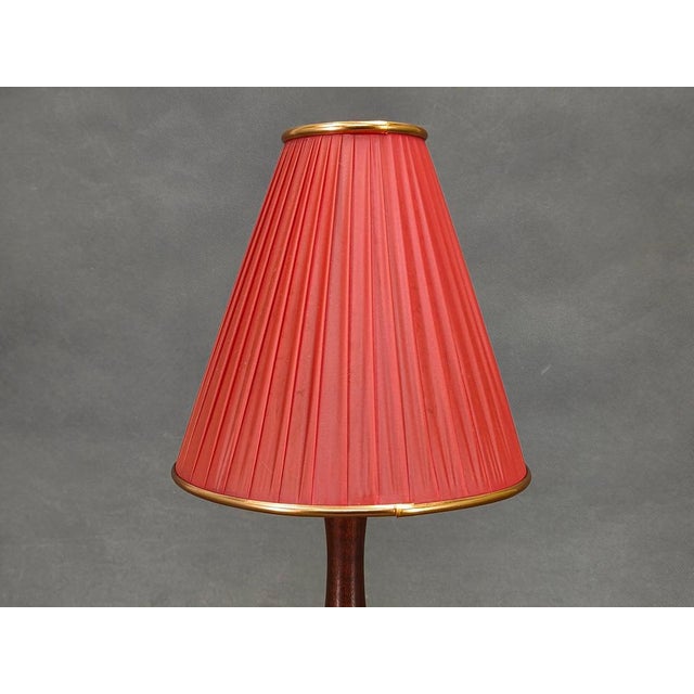 Authentic danish mid century table lamp from the 1960s, crafted from solid teak wood and fitted with a red pleated shade...
