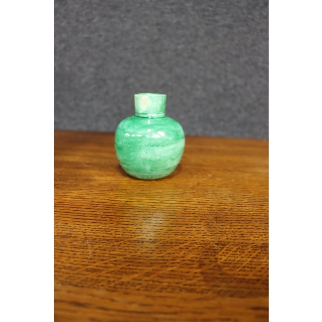 Handcrafted ceramic vase in a rounded form with a short cylindrical neck, finished in a rich green glazed surface. The...