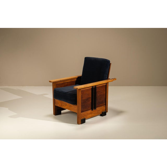 A chair like this carries its character with quiet authority. Its architectural frame, pronounced side panels and dark...