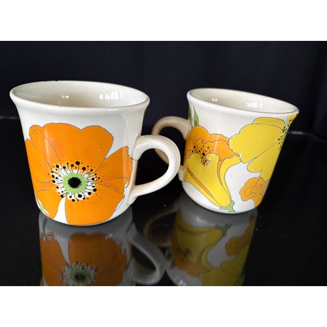 This is a beautiful set of vintage drink ware. It is a pair of glazed pottery mugs with yellow and orange flowers. It's a...