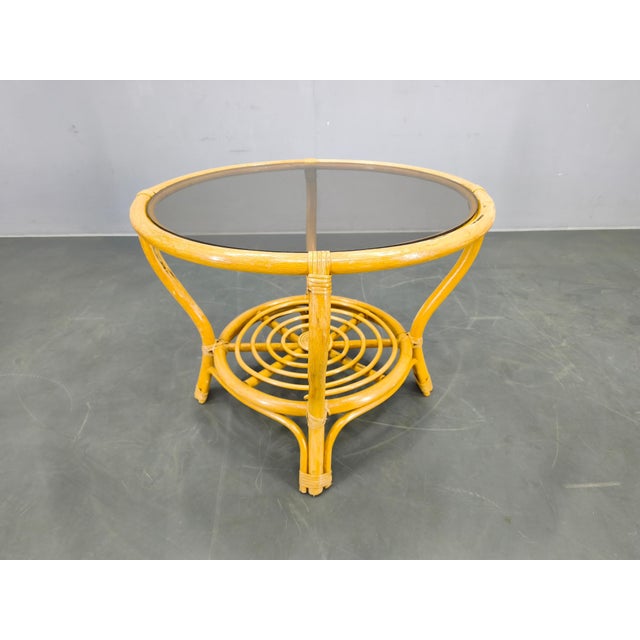 Elegant mid-century coffee table produced in Italy in the 1960s, featuring a natural rattan structure with a round glass...