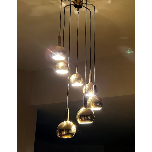 Mid century Space Age pendant light, featuring 7 brass spheres with louvered top, arranged in a circular cascade alike...