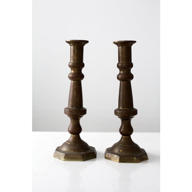 This pair of vintage brass candlestick holders offers a quiet, balanced presence, defined by turned stems and octagonal...