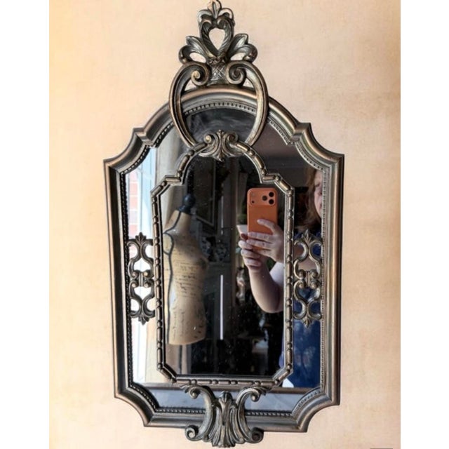 Decorative wall mirror with an ornate gold/silver finish. Elegant design adds classic charm to any room. Durable frame...