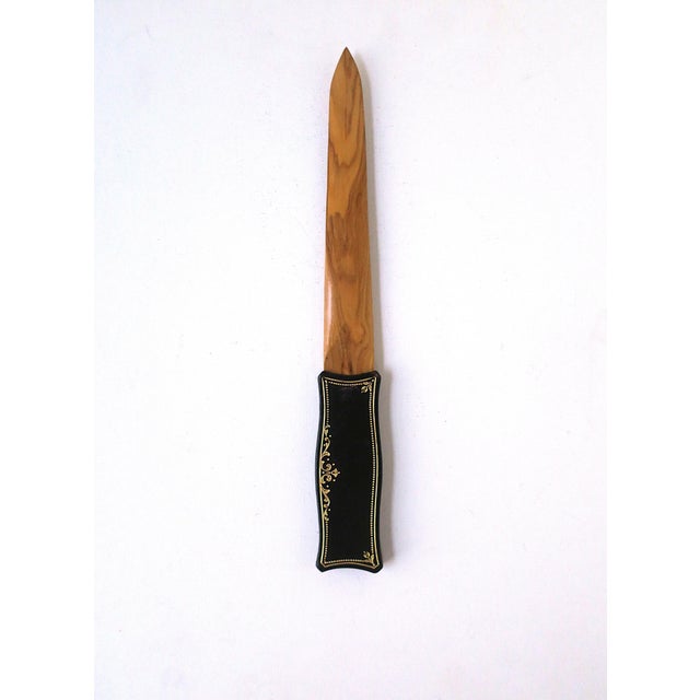 An Italian wood and leather letter opener, circa mid-20th century, Italy. Piece is blonde wood with a dark brown leather...