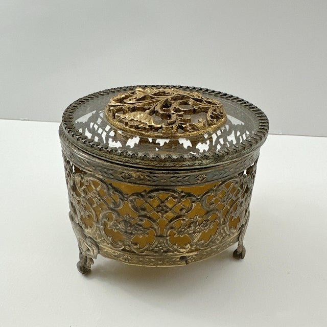Add a touch of vintage elegance to your vanity or dresser with this beautifully detailed gold tone filigree jewelry box....