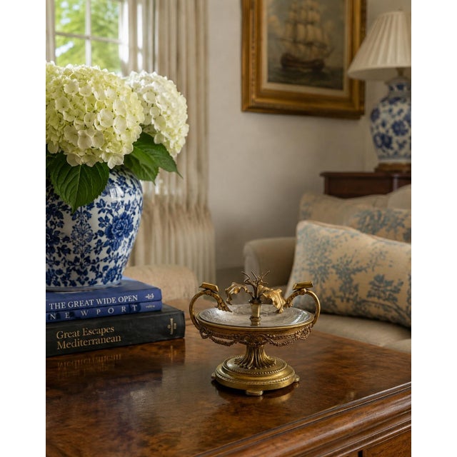 An unusually decorative circa-1940s ashtray combining warm gilded brass with a cool chrome bowl. Cast floral swags,...