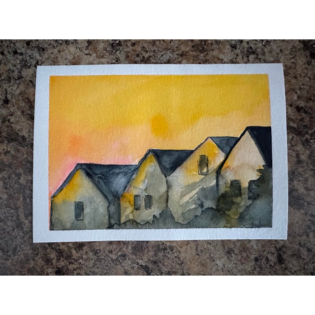 A row of cozy homes silhouetted against a glowing golden sky. The warm, radiant atmosphere paired with soft shadowed...