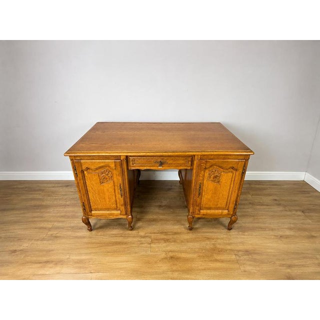 An elegant Vintage French Louis oak desk cabinet featuring a broad rectangular top, decorative carved detailing, two side...