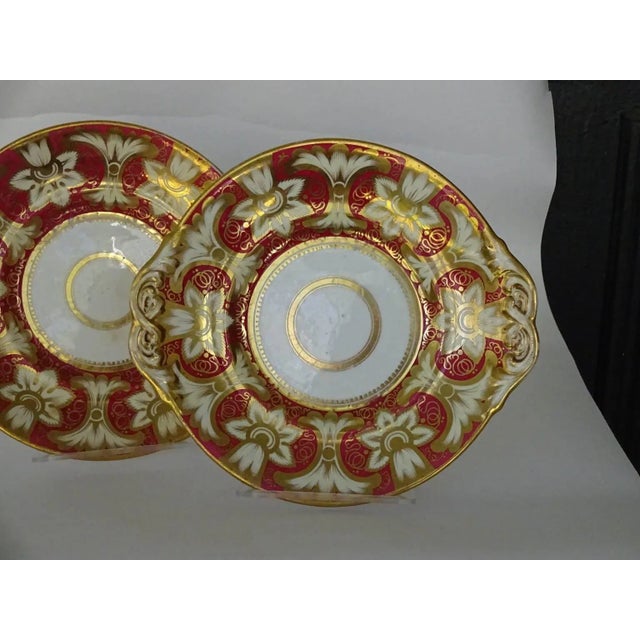 Pair of red and gold Victorian plates, on white ground. Flowers and flourishes. Ovoid shape. Probably dessert plates, but...