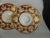 Pair of red and gold Victorian plates, on white ground. Flowers and flourishes. Ovoid shape. Probably dessert plates, but...