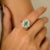 This vintage-inspired oval 0.79-carat natural emerald in the center and 0.94 carats of round halo brilliant-cut diamond...