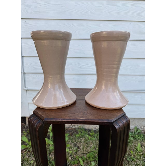 The clean, modern shape of the nude to blush colored vases start with a wide ridged rim at the top narrowing through the...
