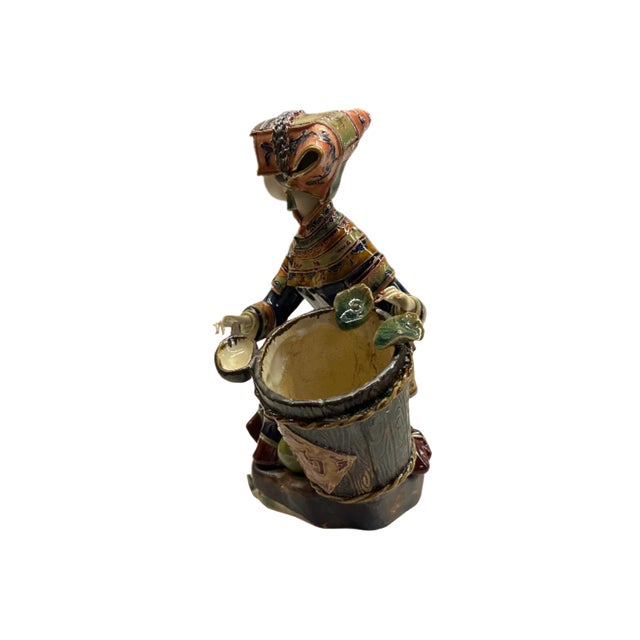 This is an intricately crafted ceramic figurine depicting a traditional scene with rich cultural details. The figure...