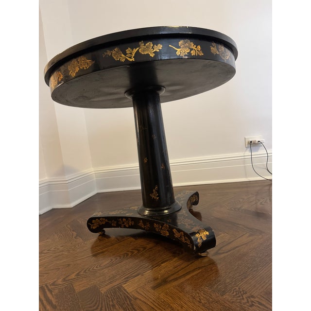 A 19th Century English Regency Chinoiserie Black and Parcel-Gilt Lacquered Center Table, with a pedestal base raised on...