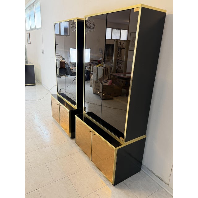 Set of two display cabinets attributed to Renato Zevi, 1970, in brass, gold-plated mirrored glass, and smoked glass. Each...
